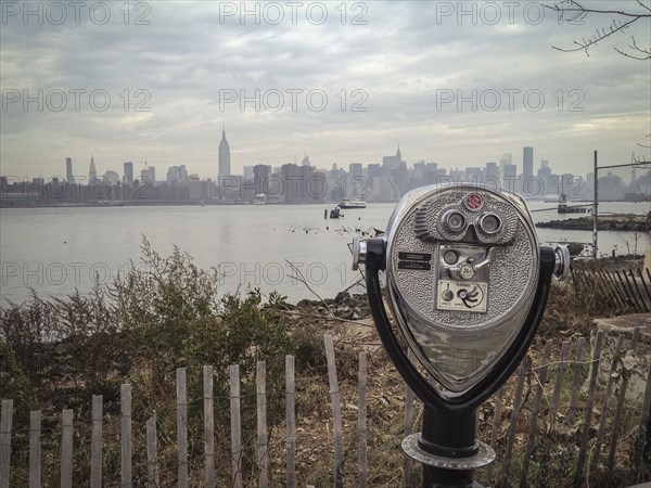 Coin-operated binoculars viewing city skyline on urban waterfront