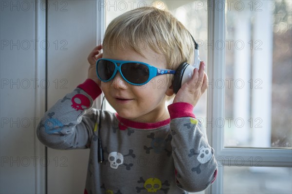 Caucasian boy wearing headphones and sunglasses indoors