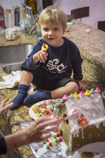 Caucasian mother and son making gingerbread house in kitchen