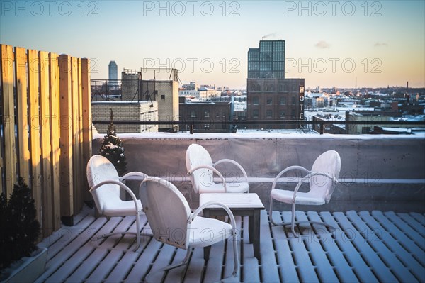 Patio furniture in snow on urban rooftop