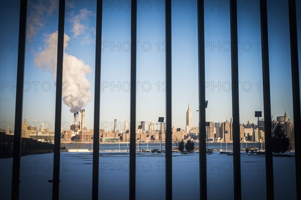 Bars in front of smokestack in city skyline