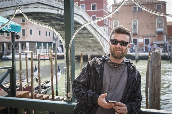 Caucasian man holding cell phone on dock