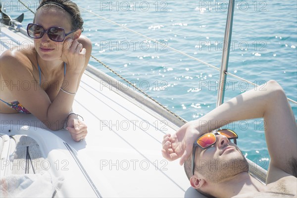 Caucasian couple sunbathing on boat deck