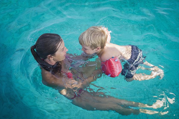 Caucasian mother teaching son to swim in pool
