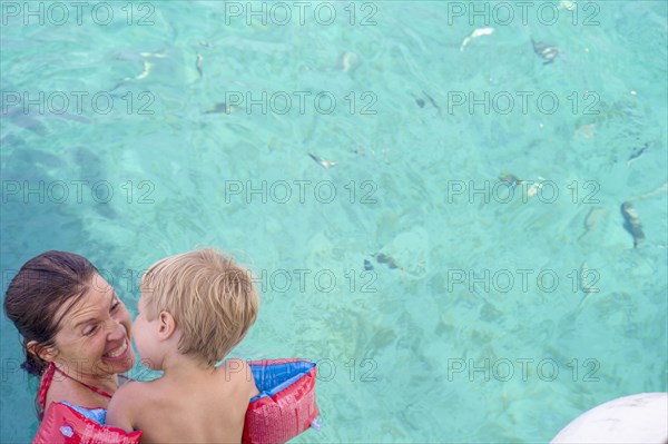 Caucasian mother teaching son to swim in pool