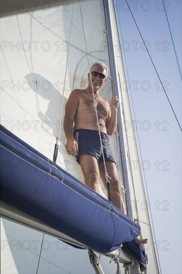 Caucasian man standing on boat sail