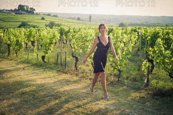 Caucasian woman walking on dirt path in vineyard