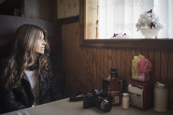 Caucasian woman sitting in diner booth near window