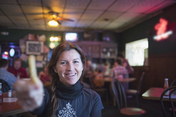 Caucasian woman offering french fry in bar