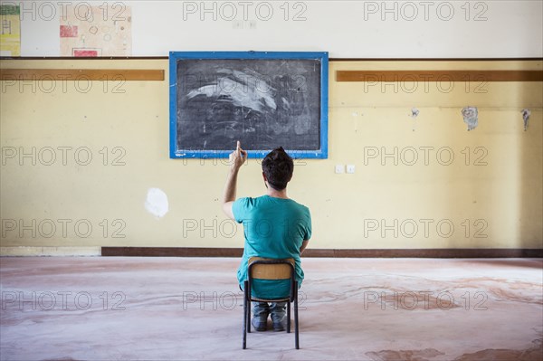 Caucasian student sitting in empty classroom