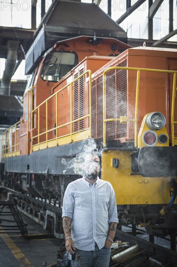 Caucasian man blowing smoke in train yard