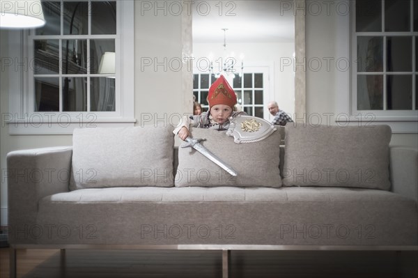 Caucasian boy playing with toy sword in living room