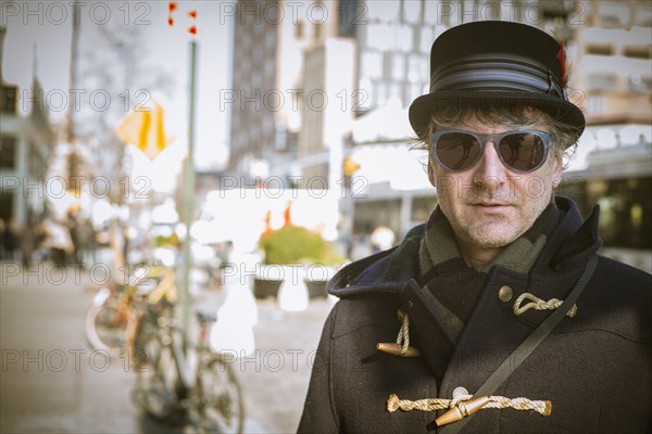 Caucasian man in top hat standing on city sidewalk