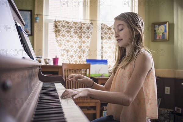 Caucasian girl playing piano in living room