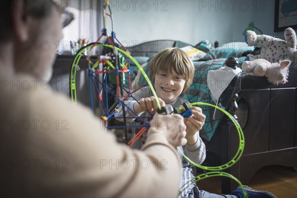 Caucasian father and son playing with toys in bedroom