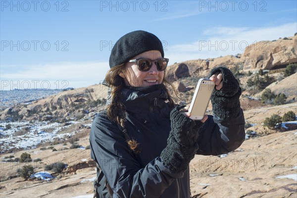 Caucasian woman taking cell phone photograph on hillside