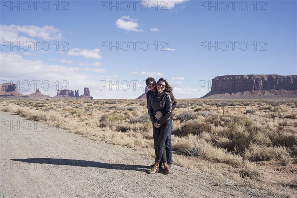 Caucasian couple hugging on desert dirt road