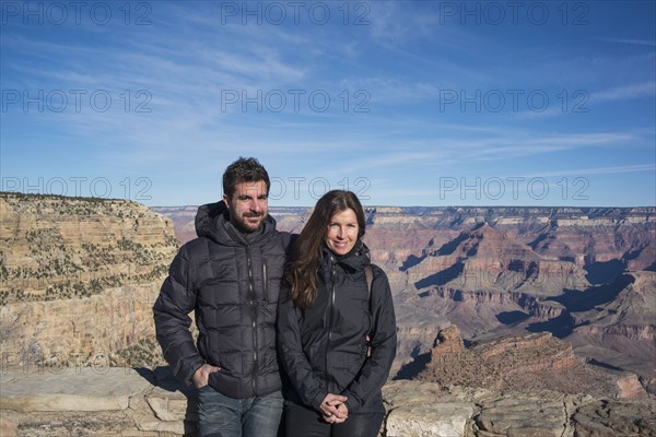 Caucasian couple standing over Grand Canyon