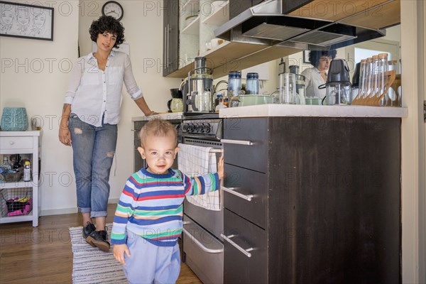 Caucasian mother watching baby son in kitchen