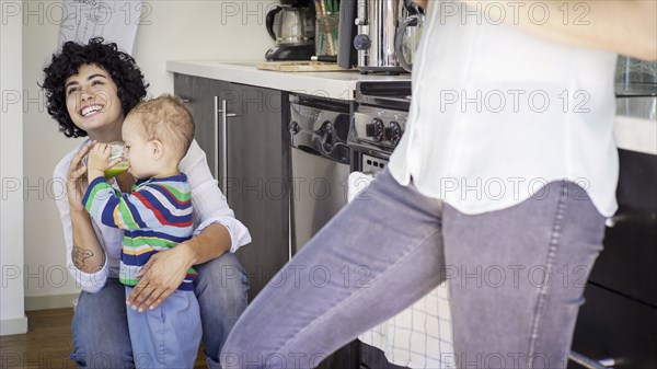 Caucasian lesbian mothers and baby son in kitchen