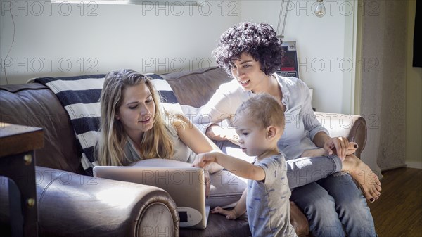 Caucasian lesbian mothers and baby son on sofa