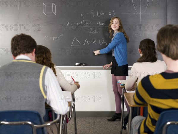 Student writing on chalkboard in classroom