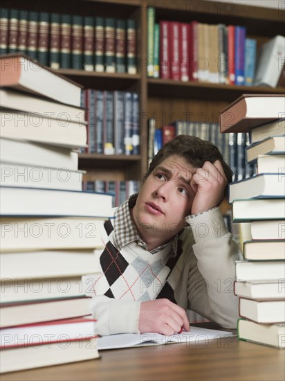 Student staring at stacks of books in library