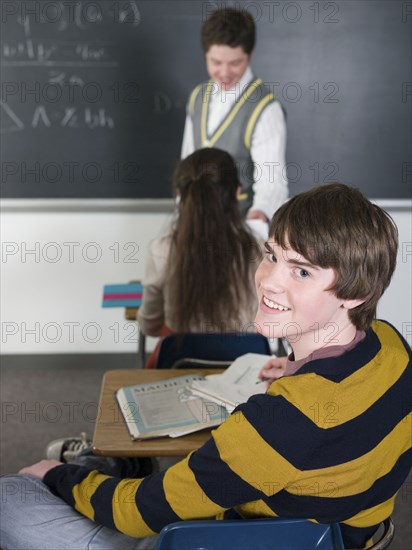 Student smiling at desk in classroom