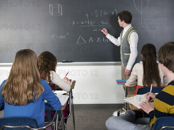 Teacher writing on chalkboard in classroom