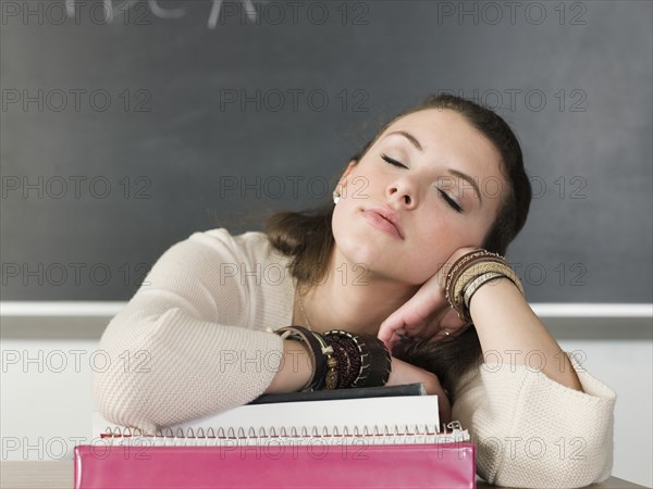 Bored student sleeping at desk in classroom