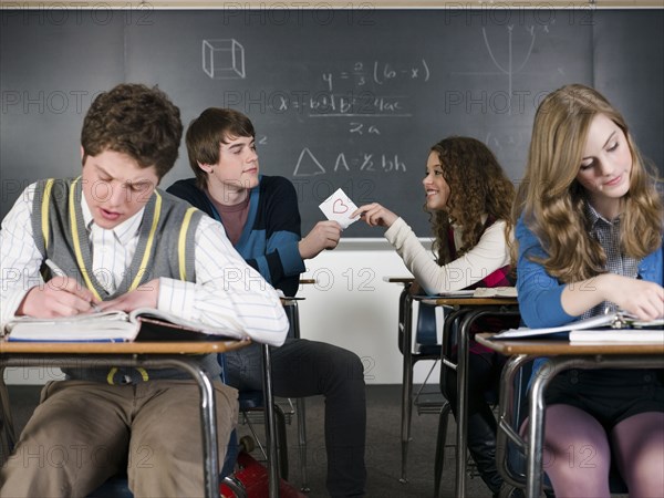 Students passing love note in classroom