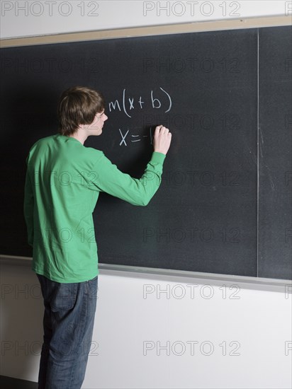 Student writing on chalkboard in classroom