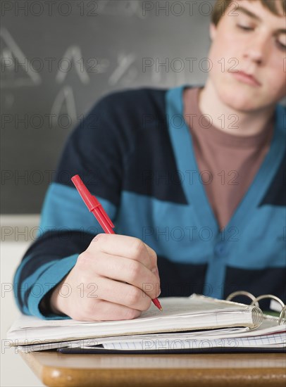 Student writing notes at desk in classroom