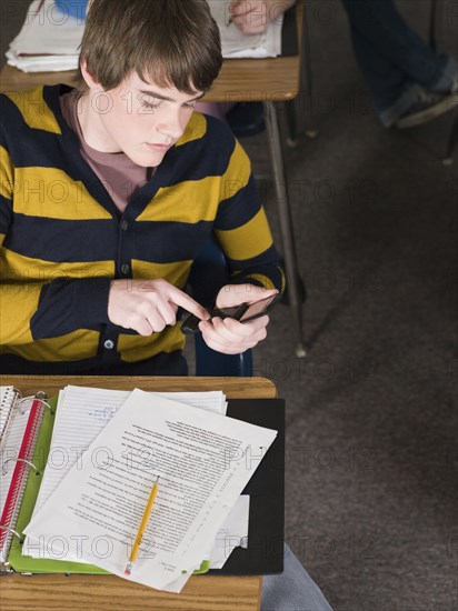 Student using cell phone at desk in classroom