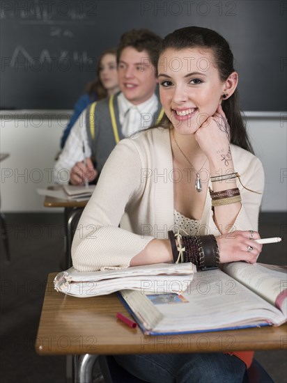 Student smiling at desk in classroom