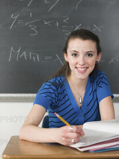 Student writing notes at desk in classroom