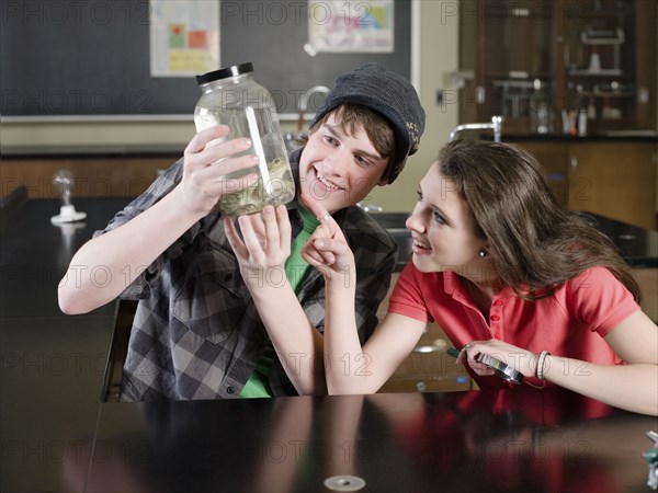 Students examining frog in science lab classroom