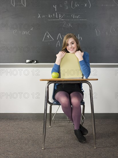 Student holding book at desk in classroom