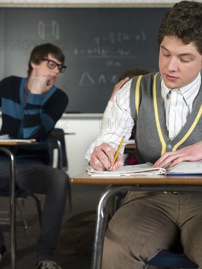 Student writing notes at desk in classroom