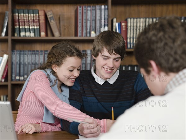 Students writing at desk in library