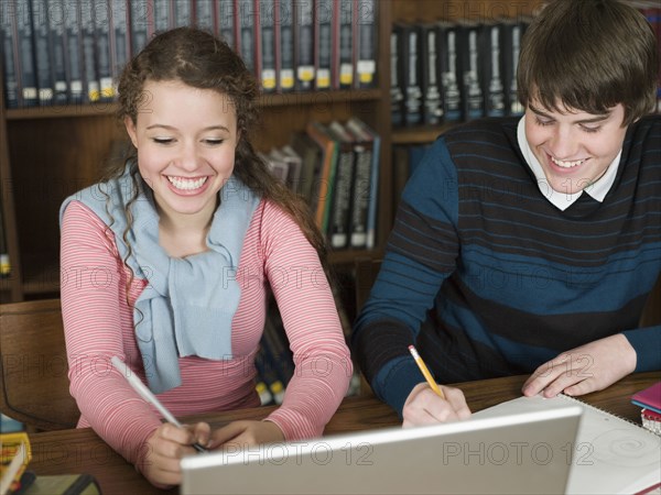 Students writing notes at desk in library