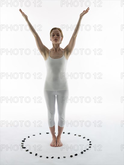 Caucasian woman practicing yoga in ring of stones