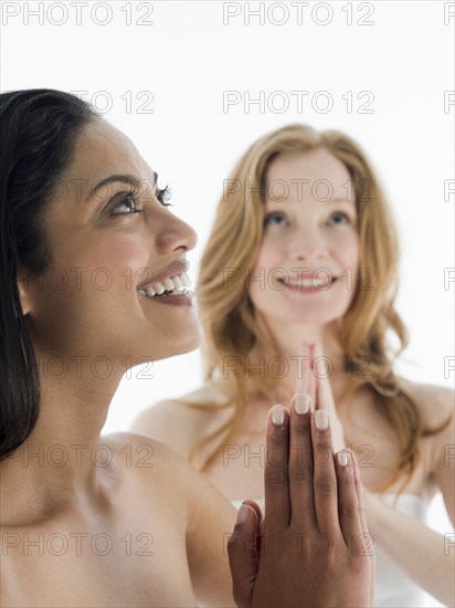 Close up of smiling women praying with hands clasped