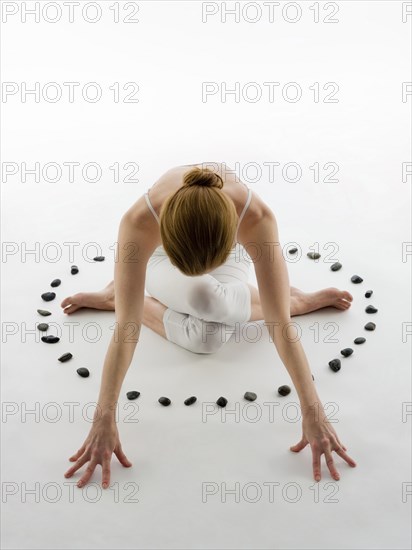 Caucasian woman practicing yoga in ring of stones