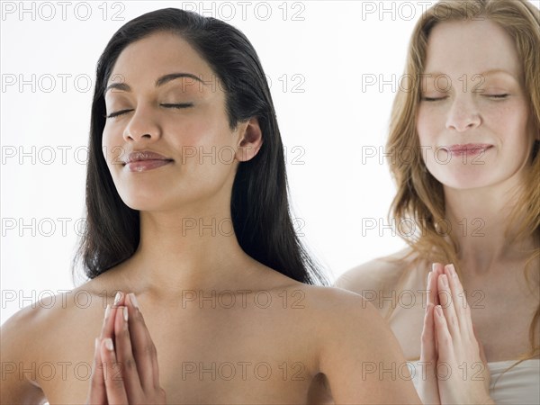 Smiling women meditating with hands clasped