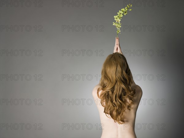 Rear view of nude Caucasian woman holding leaves