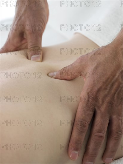 Close up of masseuse massaging back of woman