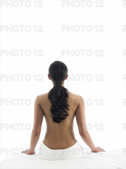 Rear view of nude woman sitting on massage table
