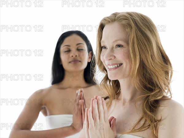 Women meditating with hands clasped