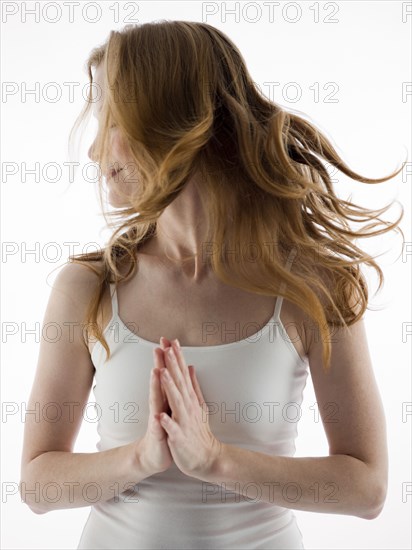 Caucasian woman tossing her hair with clasped hands